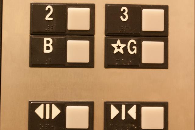 Photograph of elevator buttons found in the Lassounde building at York University. The embossed type on button for the ground floor (upper right) says ☆G but the braille says “main”.